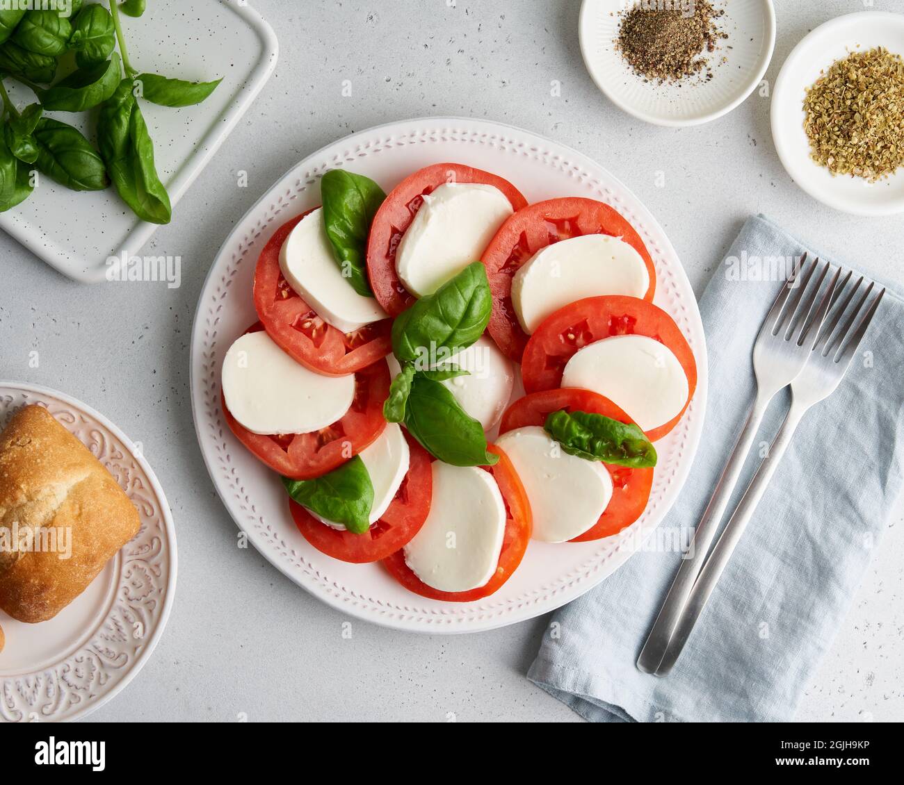 Klassische italienische Caprese-Vorspeise mit Tomaten, Mozzarella, Basilikum, Brot und Orangen Stockfoto