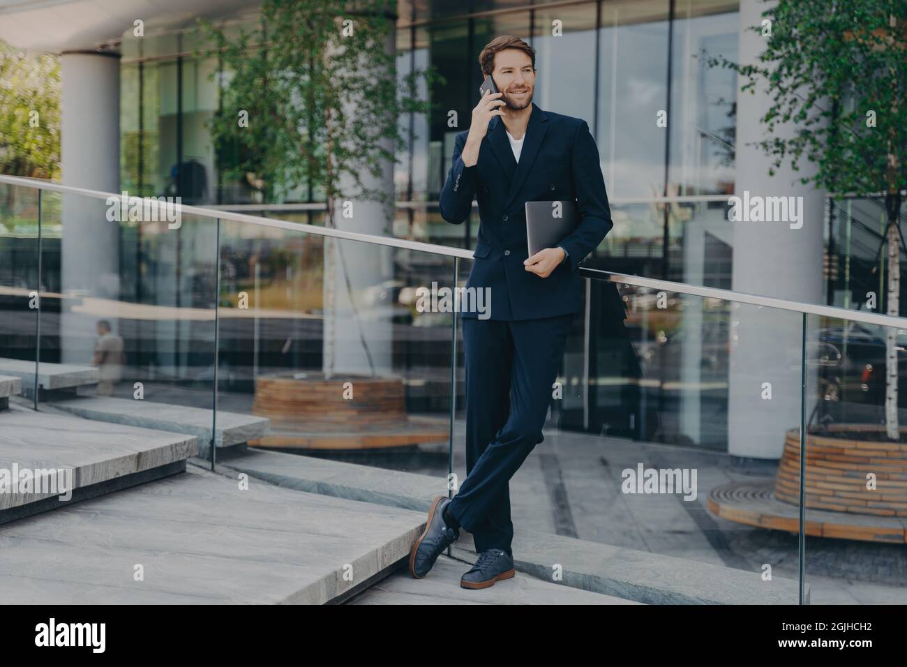 In voller Länge Aufnahme von eleganten Geschäftsmann in formeller Kleidung hat Telefongespräch Stockfoto