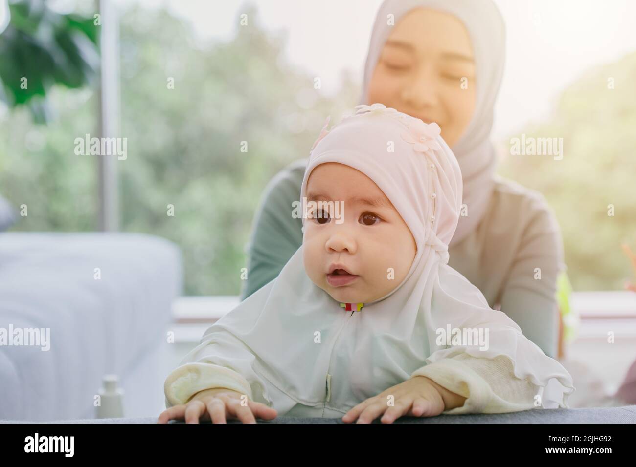 Muslim Mutter Blick auf ihr Baby glücklich lächelnd Kleinkind häusliche Pflege zusammen niedlich schöne Kindheit innen. Stockfoto