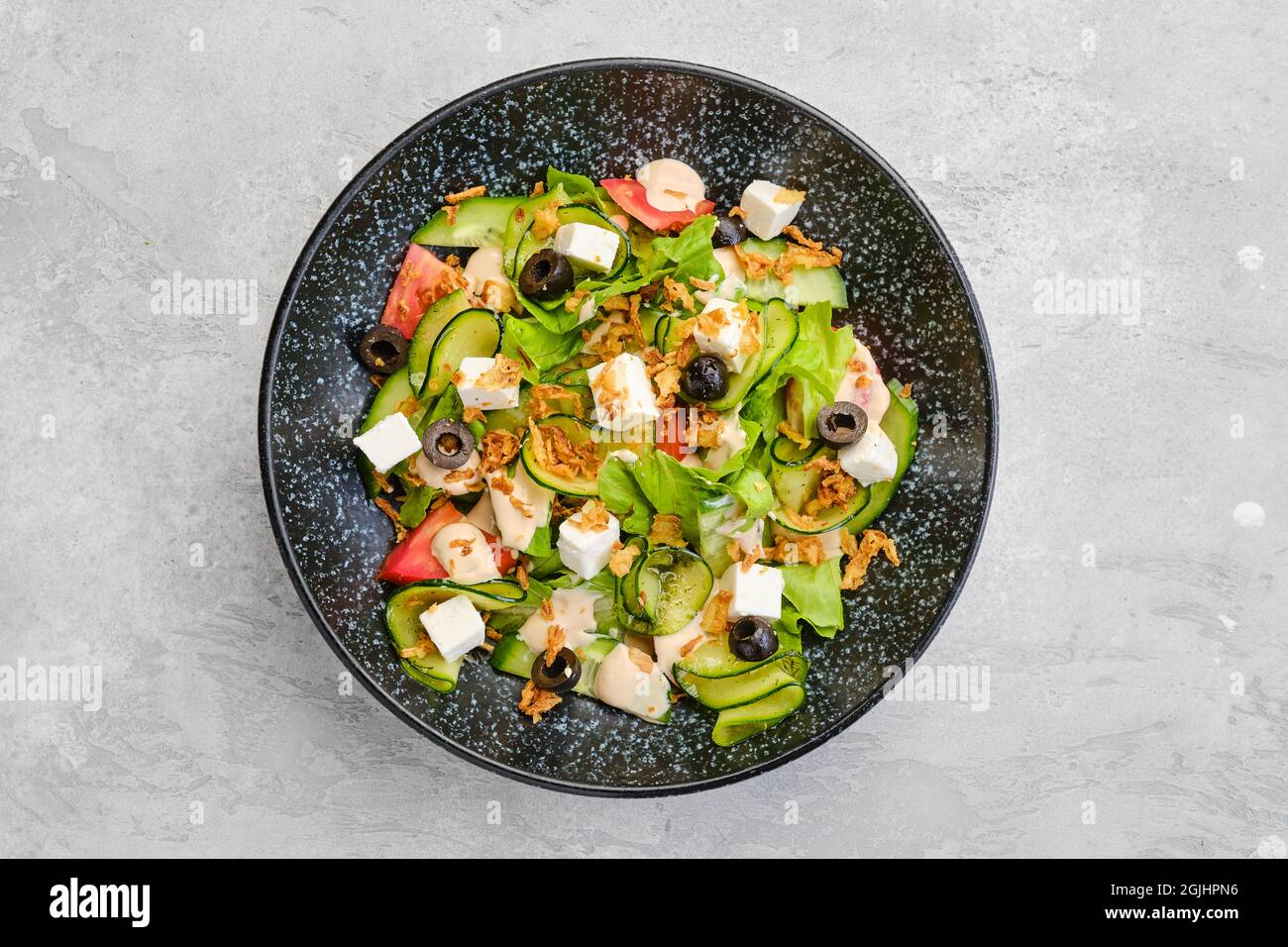 Blick von oben auf Salat mit Salat, Gurke, Oliven, Tomaten, Feta-Käse und Speck-Chips Stockfoto