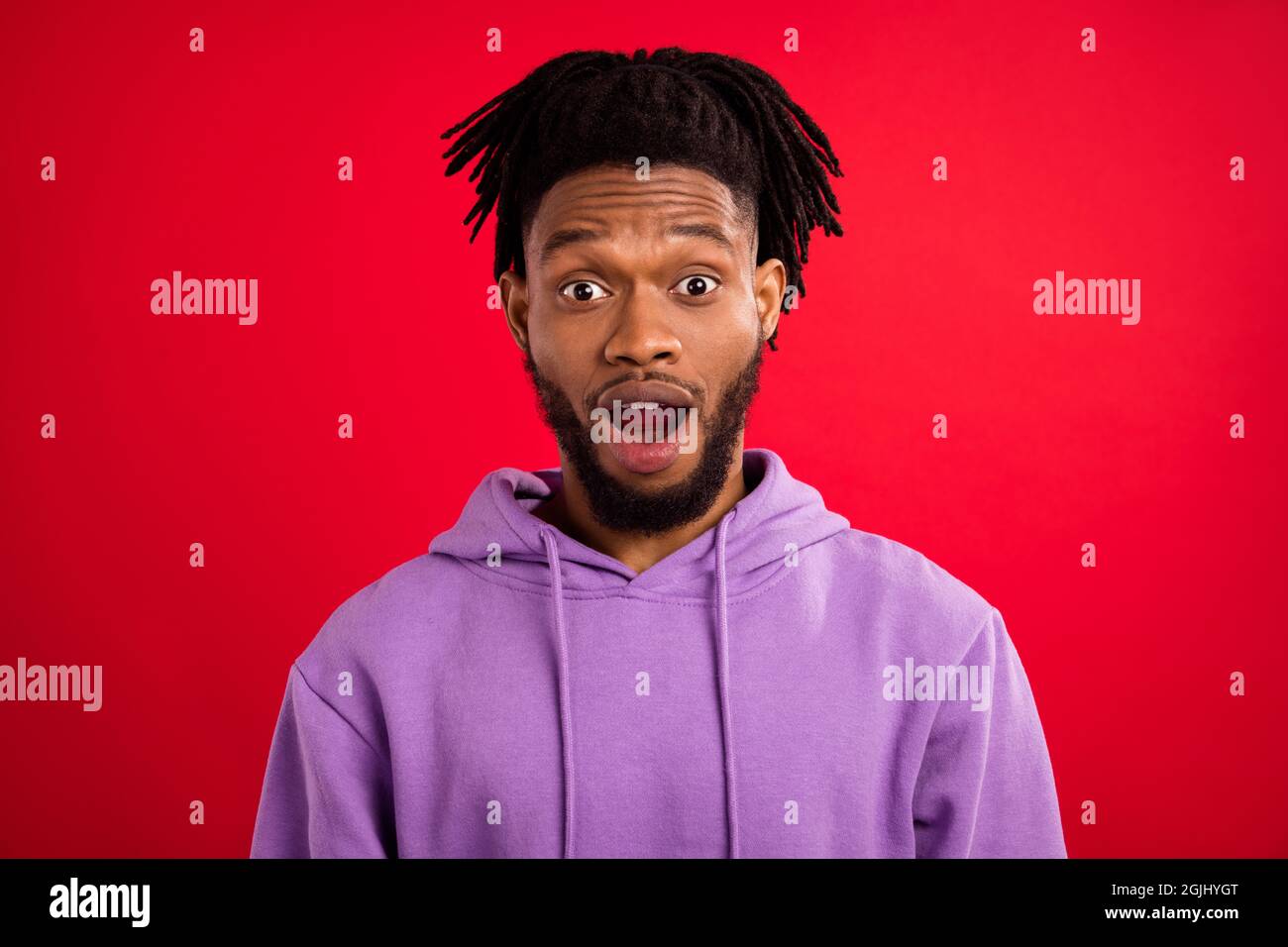 Foto Porträt Mann mit Dreadlocks starren in Sportswear isoliert lebendige rote Farbe Hintergrund erstaunt Stockfoto