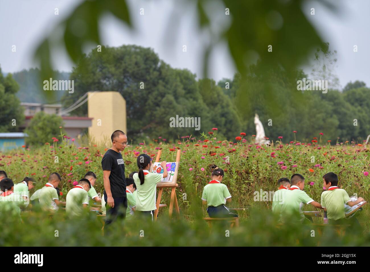 (210910) -- NANCHANG, 10. September 2021 (Xinhua) -- Yin Dafu unterrichtet eine Malstunde im Freien auf dem Bauernhof der Zhongxin Grundschule in der Gemeinde Zhaixia im Bezirk Yuanzhou, Yichun, Provinz Jiangxi in Ostchina, 1. September 2021. Im Jahr 1997 kam der 19-jährige Yin Dafu freiwillig in die Gemeinde Zhaixia, wo er die Karriere eines ländlichen Lehrers begann. China plant, 84,330 2021 Hochschulabsolventen als Lehrer an ländlichen Grund- und Mittelschulen zu rekrutieren, um die ländliche Belebung zu fördern. Die Rekrutierung ist hauptsächlich für die einst verarmten Gebiete und die von ethnischen Minderheiten bewohnten Gebiete bestimmt, um p zu konsolidieren Stockfoto