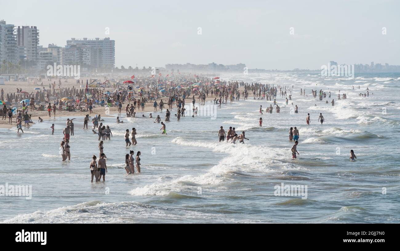 Gandia, Spanien - 26. Juli 2021: Menschenmenge am Sandstrand und stürmisches Meer mit hohen Wellen an der Küste Stockfoto