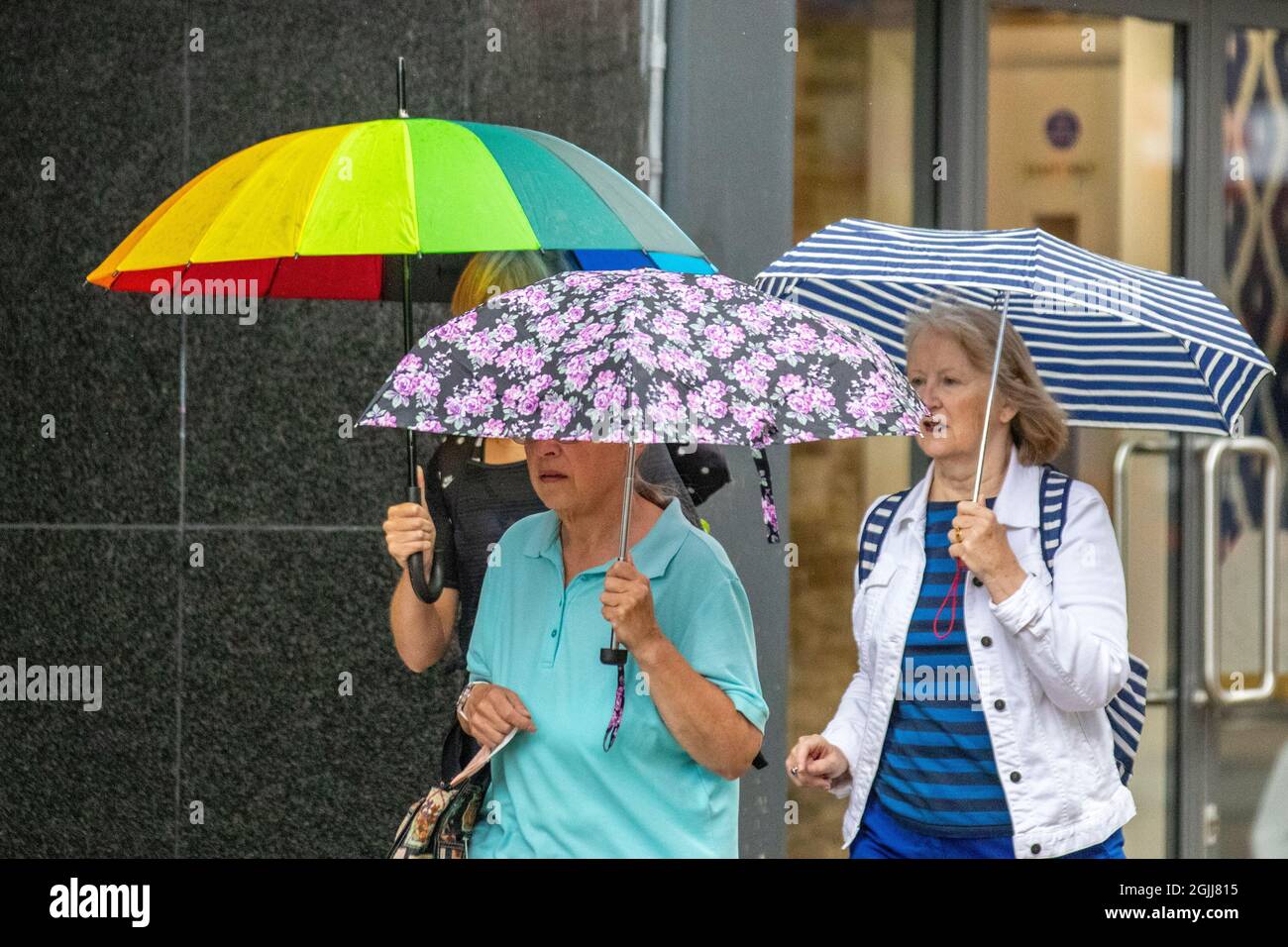 Drei Frauen mit bunten Regenschirmen an einem regnerischen Tag in Preston, Lancashire. Wetter in Großbritannien 10. September 2021. Geschäfte, Shopper, Shoppen an einem Showery-Tag im Stadtzentrum von Preston. Kredit; MediaWorldImages/AlamyLiveNews Stockfoto