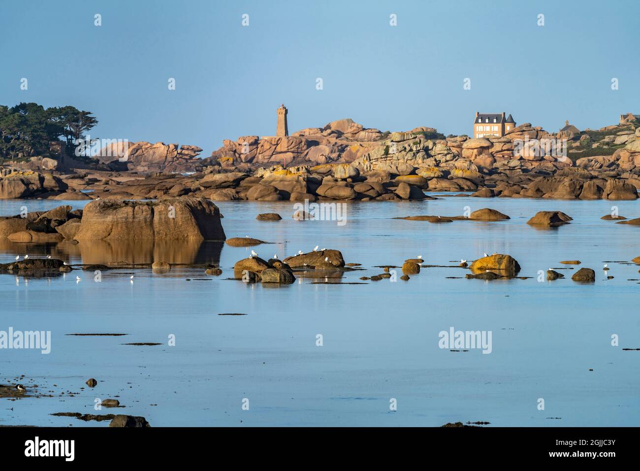 Die Felsen der rosa Granitküste Côte de Granit Rose an der Baie de Sainte Anne bei Tregastel mit Blick auf die Maison Gustave Eiffel und den Leuchtturm Stockfoto