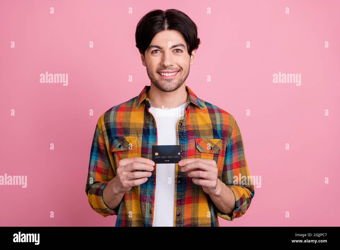 Foto von charismatischen ziemlich jungen Gentleman tragen kariertes Outfit halten Kreditkarte lächelnd isoliert rosa Farbe Hintergrund Stockfoto