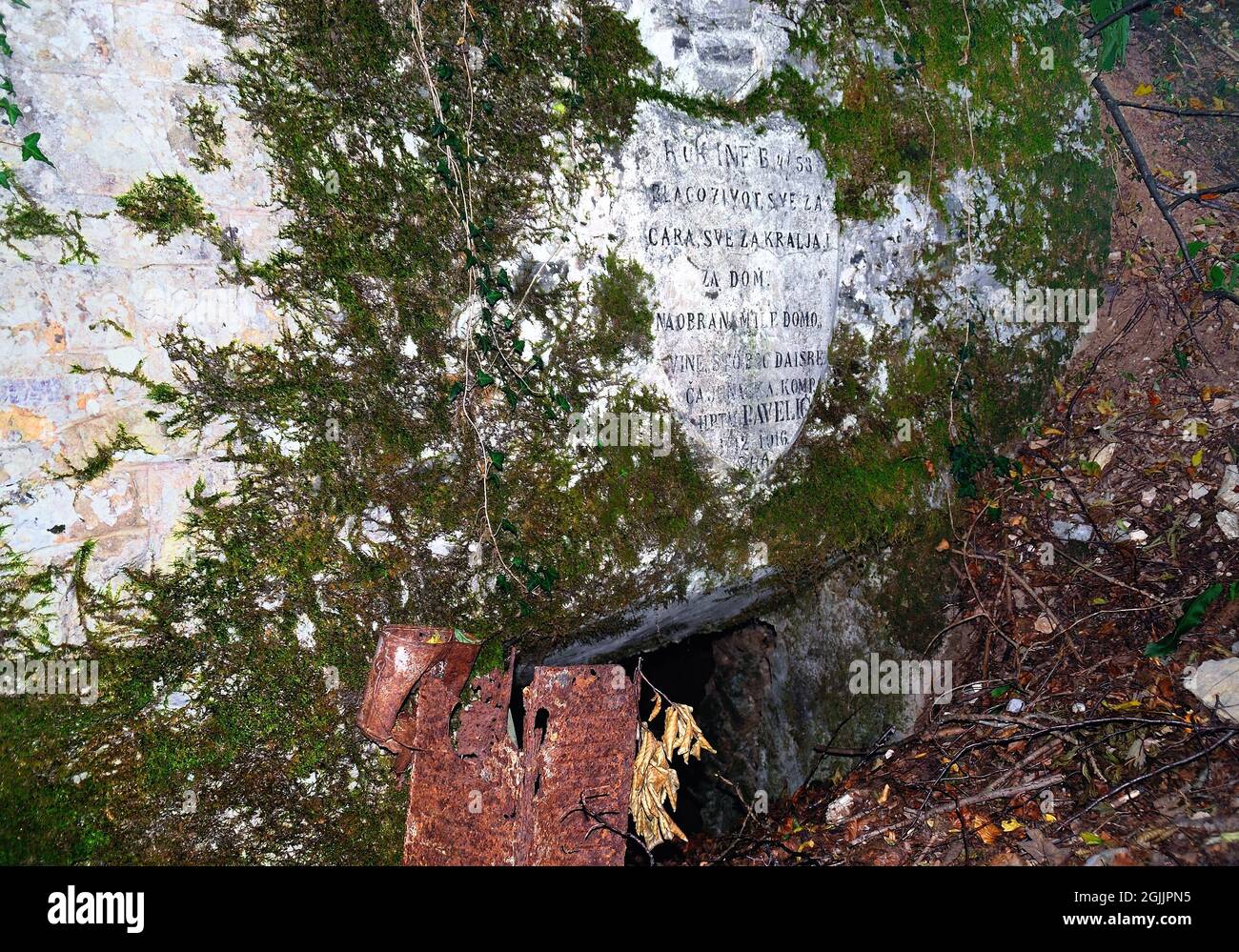 Slowenien, Mengore Hill, 1. Weltkrieg. An einem abgelegenen Ort, der mit einigen Schwierigkeiten erreicht werden kann, entlang des österreichischen Grabens, der bis auf eine Höhe von 510 m ansteigt.Blick auf den Fluss Soca, gibt es ein großes Wappen, eingraviert auf dem Felsen. Es ist am Eingang einer verschlick-up-Höhle zu sehen. Die kroatische Inschrift besagt: „Gott rettet die tapfere Kraft von Capt. Pavelisch bei der Verteidigung seines geliebten Landes“. Auf einer Seite des Höhleneingangs befindet sich ein Metallofen. Stockfoto