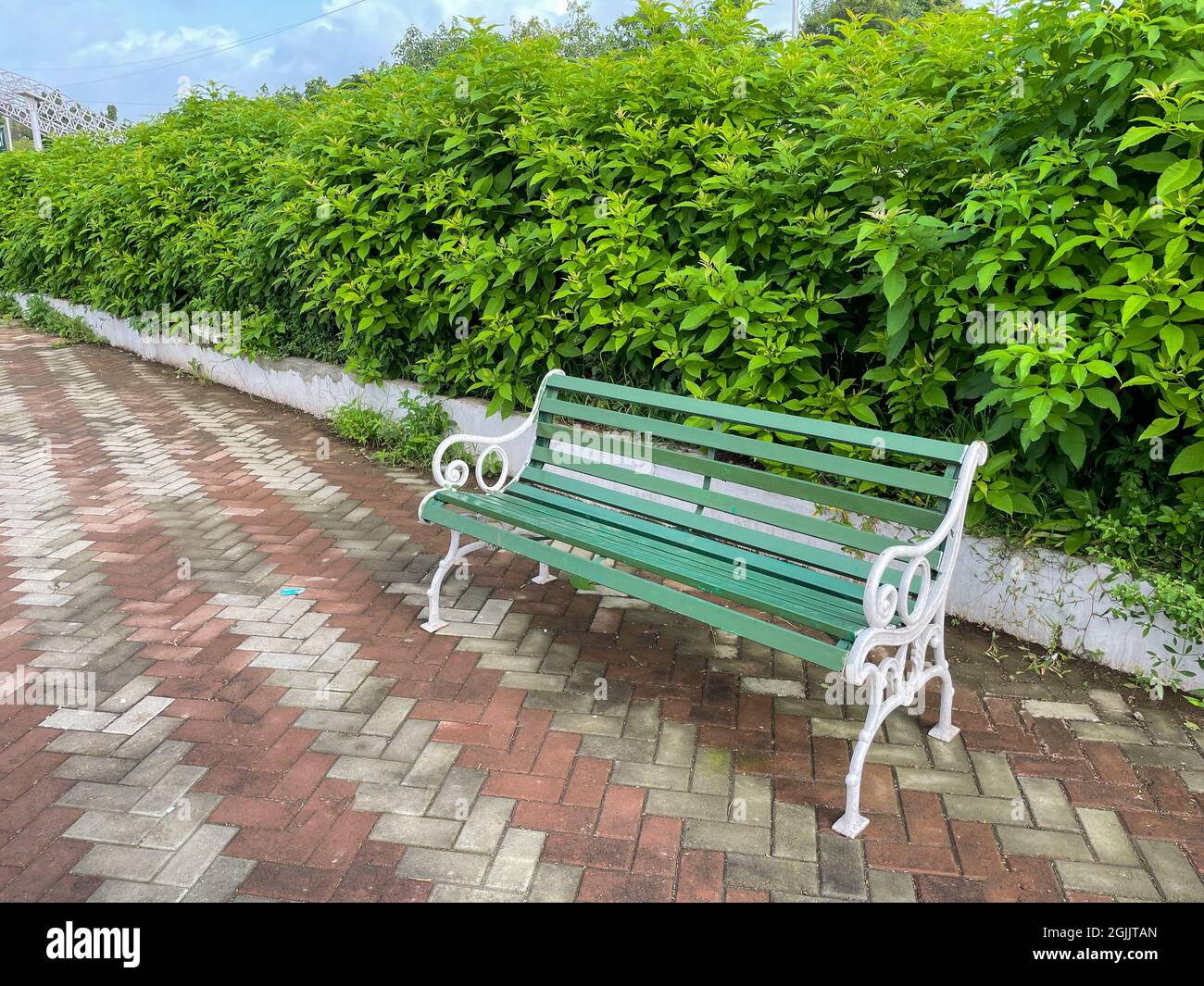 Eine schöne, grün und weiß lackierte Bank, die in einem Park mit einer ruhigen und grünen Umgebung platziert ist Stockfoto