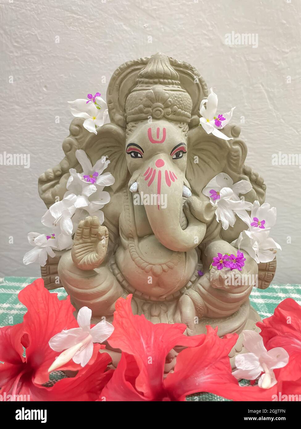Lord Ganesh Idol aus Schlamm gemacht und mit weißen und roten Blumen geschmückt Stockfoto