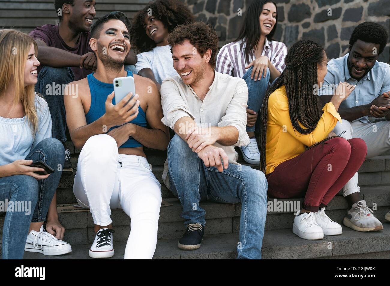 Junge multirassische Gruppe von Freunden mit dem mobilen Smartphone auf der Treppe sitzen - Jugend Millennial Lifestyle-Konzept Stockfoto