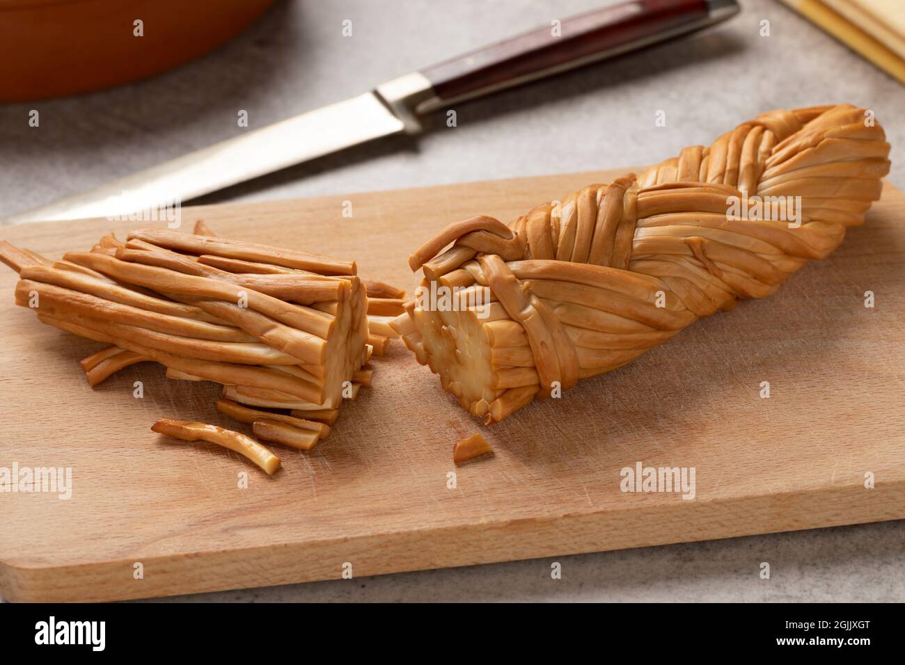 Geräucherte geflecherte Käseschnitte, genannt Chechil, aus der Adyghe Republik auf einem Schneidebrett aus nächster Nähe Stockfoto