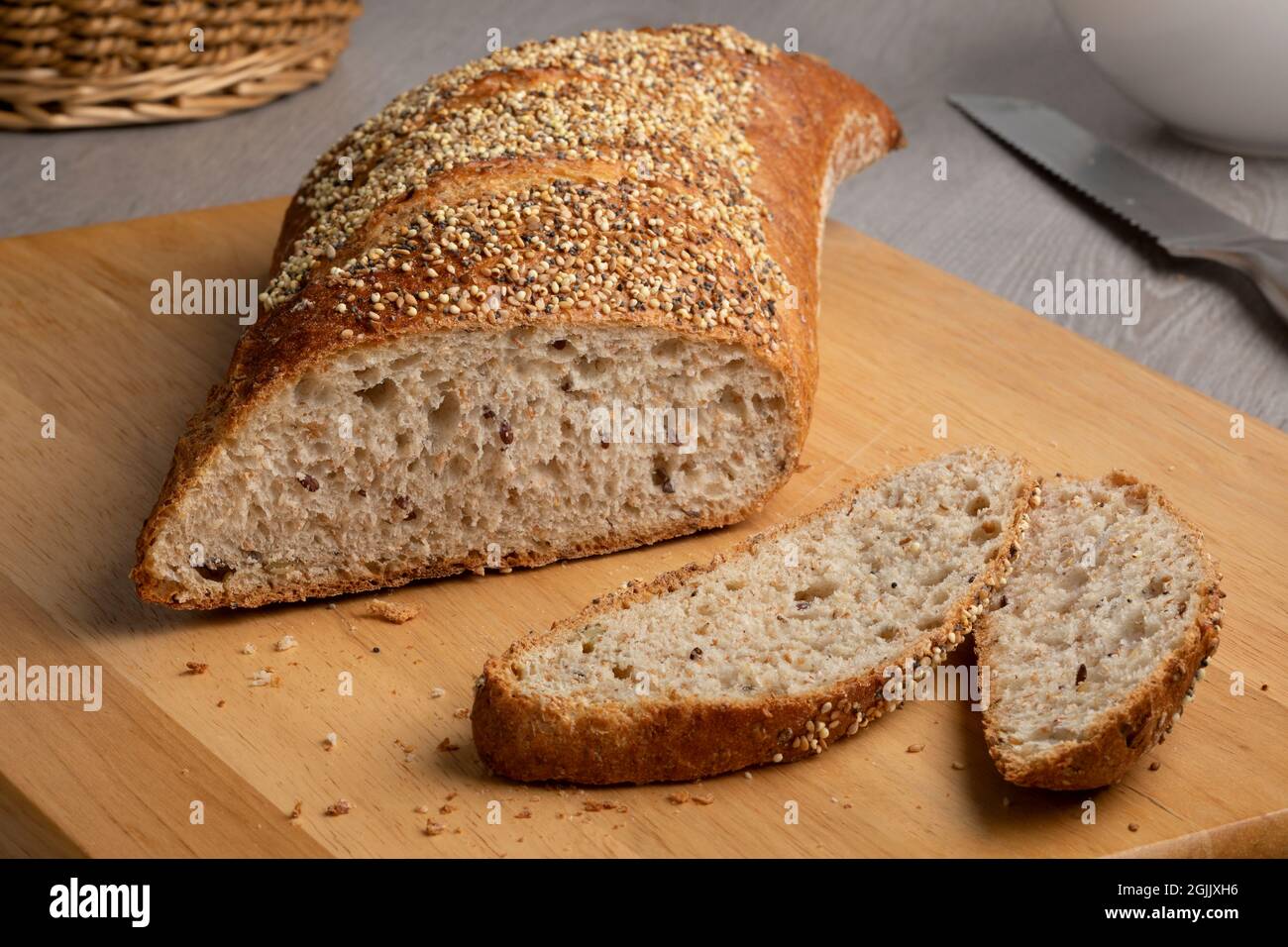 In Scheiben geschnittener traditioneller Sauerteig-Laib Brot in einer besonderen Form mit Samen auf einem Schneidebrett Stockfoto