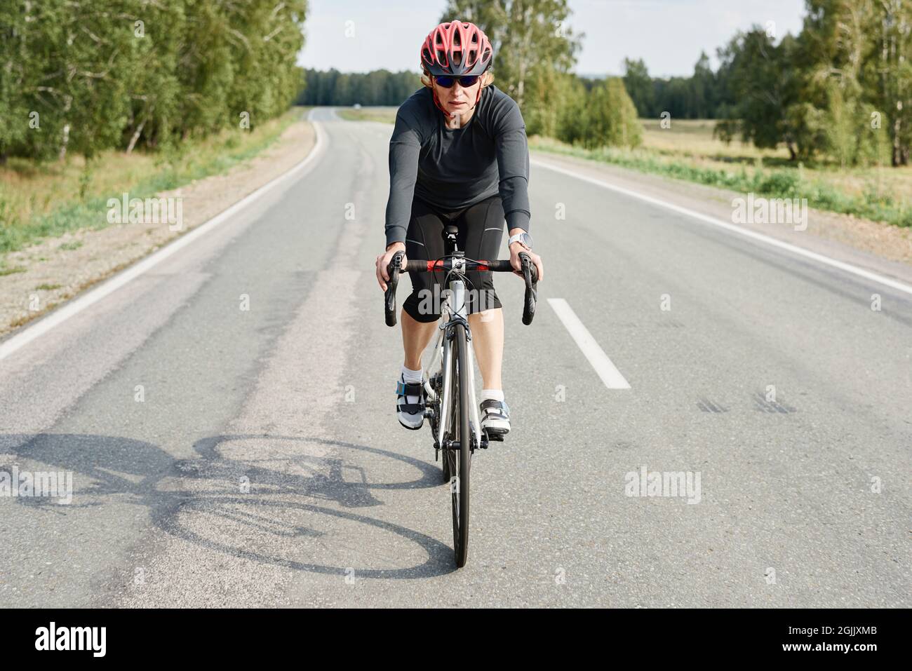 Frau in Sportkleidung und Helm auf einer Straße mit Mountainbike fahren Stockfoto