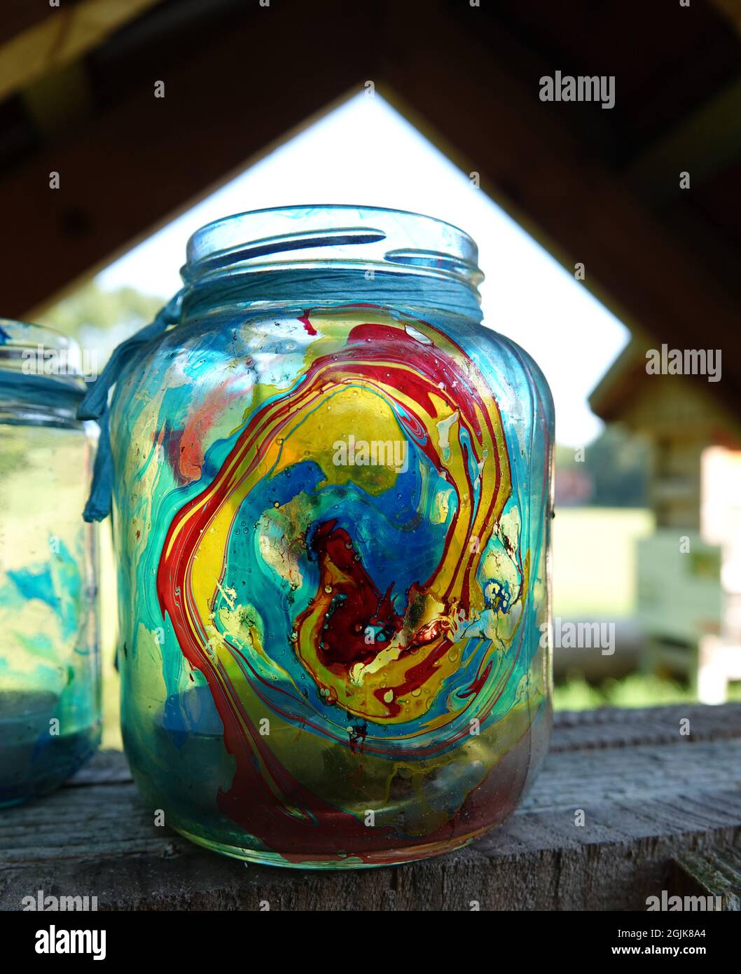 Ein Glasgefäß mit Farbe und einer Teeleuchte im Inneren, die auf einem offenen Schuppen steht Stockfoto