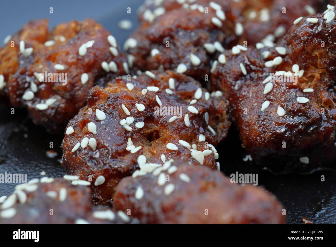 Klebrige asiatische Blumenkohlbisse zerschlagen, frittiert und in asiatischer BBQ-Sauce geworfen, bestreut mit gerösteten Sesamsamen und Frühlingszwiebeln Stockfoto