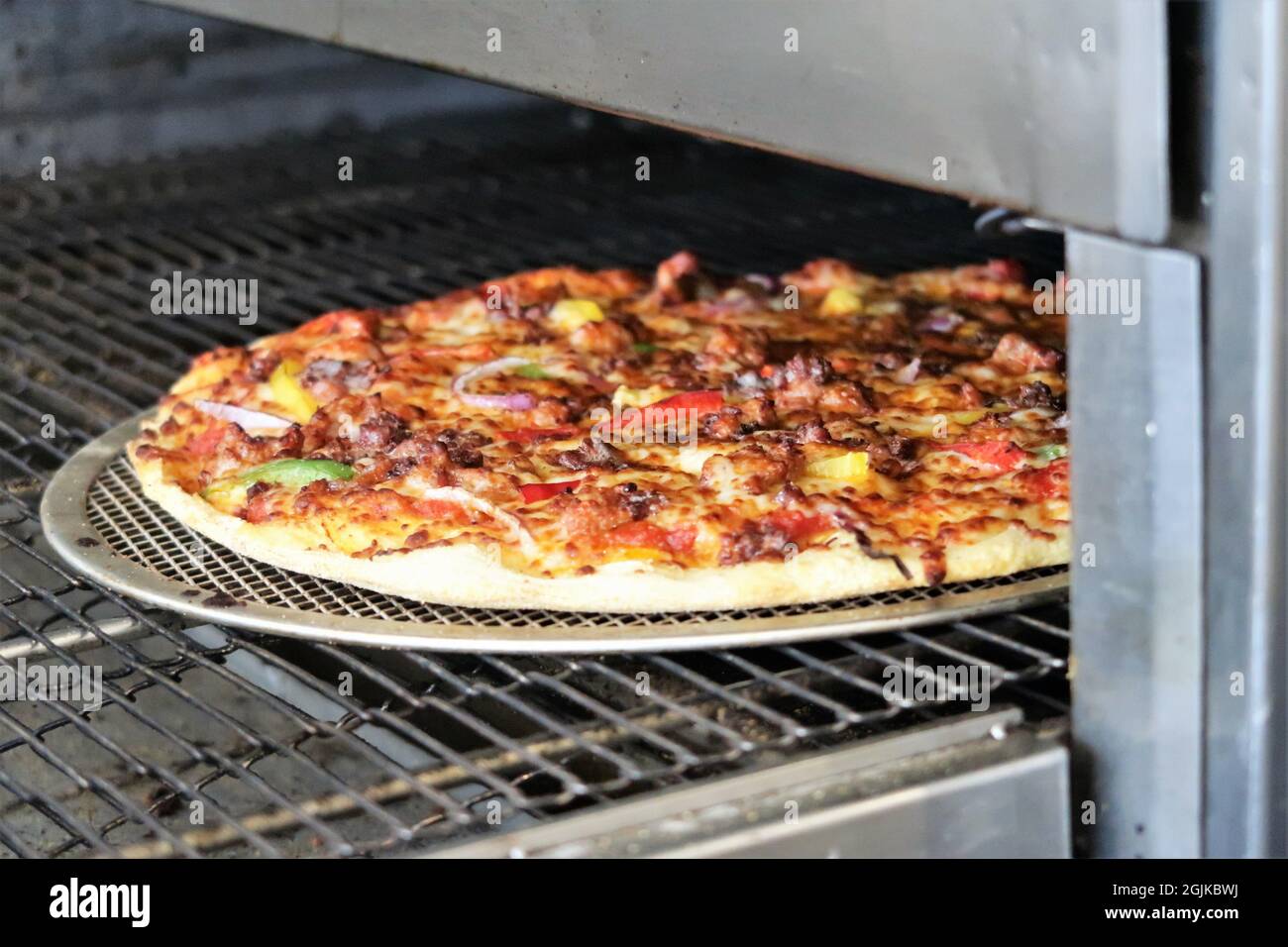 Leckere Pizza mit viel Käse und Zutaten, die im Ofen gekocht werden Stockfotografie Alamy