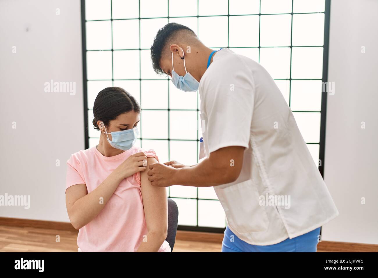 Junge Krankenschwester Mann legte Band Hilfe auf Frau Arm in der Klinik. Stockfoto