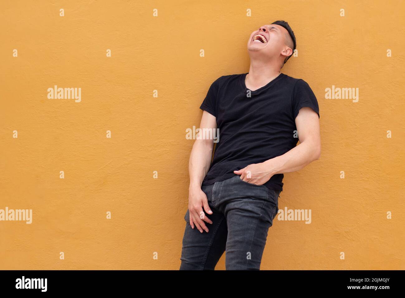 Lateinischer Mann, der laut lacht und schwarzes Hemd trägt. Natürliches Lachen und Bauchlachen Stockfoto