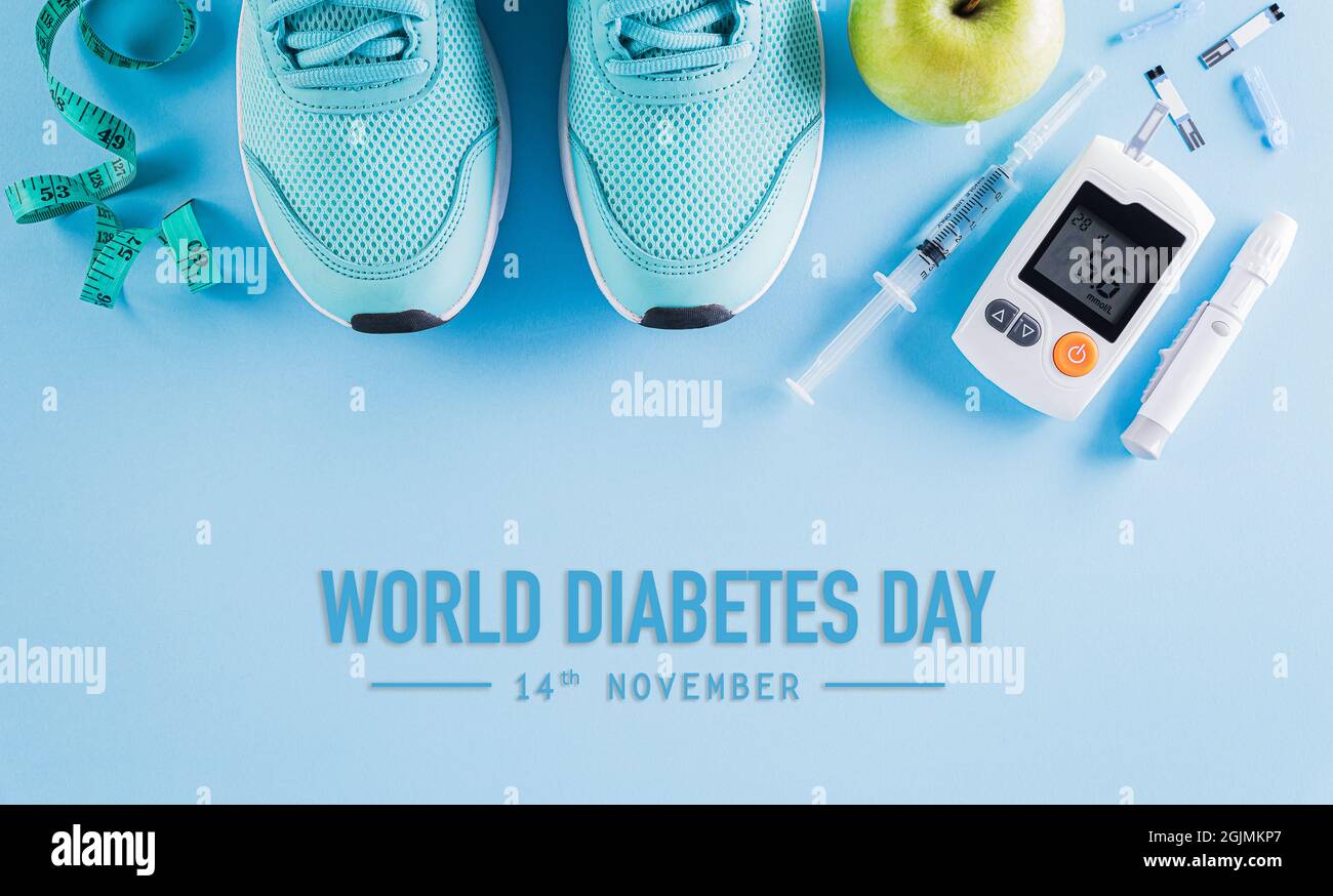 Draufsicht auf Diabetes-Tester-Set mit Sportschuhen, Maßband und grünem Apfel auf hellblauem pastellfarbenem Hintergrund. Konzept des Welt-Diabetes-Tages. Stockfoto