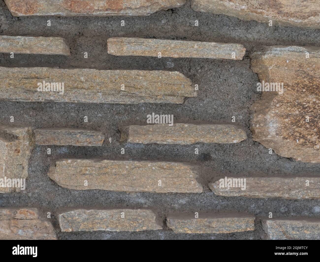 Rustikale Wand aus rauen Steinziegeln Stockfoto