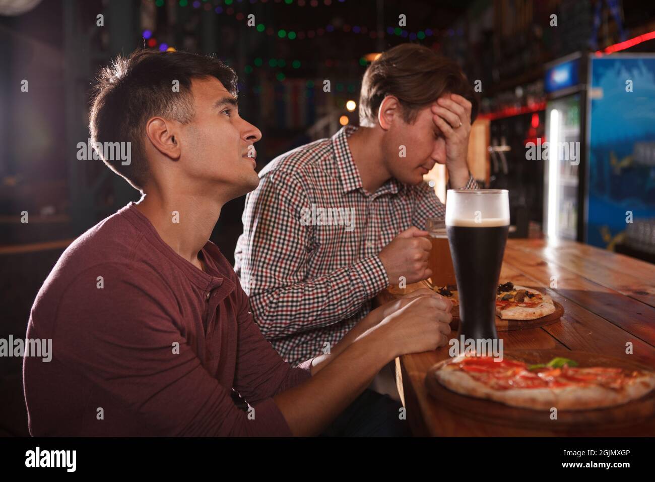 Zwei Mann, die traurig aussuchten, nachdem sie ein Spiel im Bierkneipe gesehen hatten Stockfoto