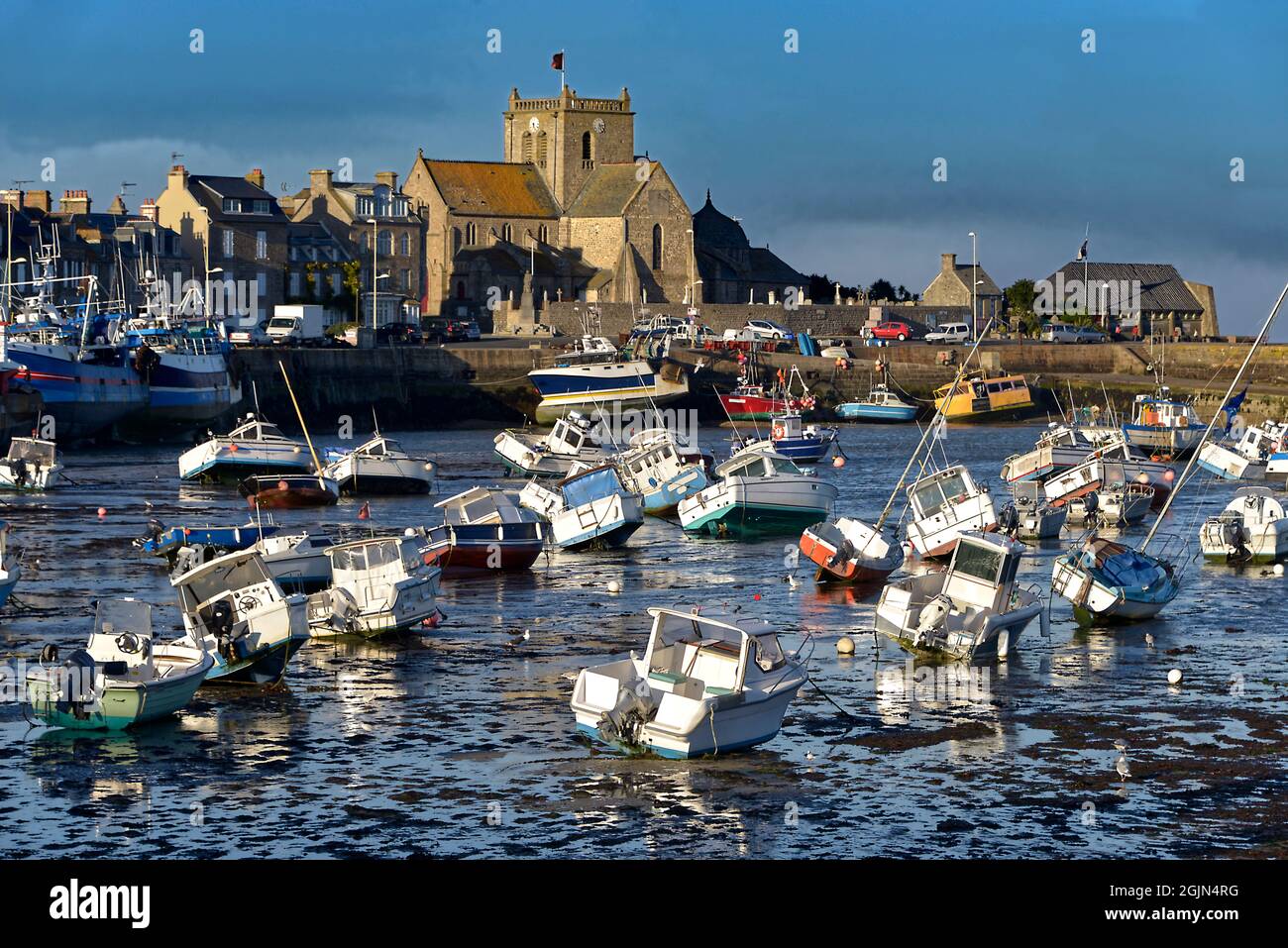 Hafen bei Ebbe am Ende des sonnigen Tages und Kirche Saint-Nicolas von Barfleur, eine Gemeinde auf der Halbinsel Cotentin in Frankreich Stockfoto
