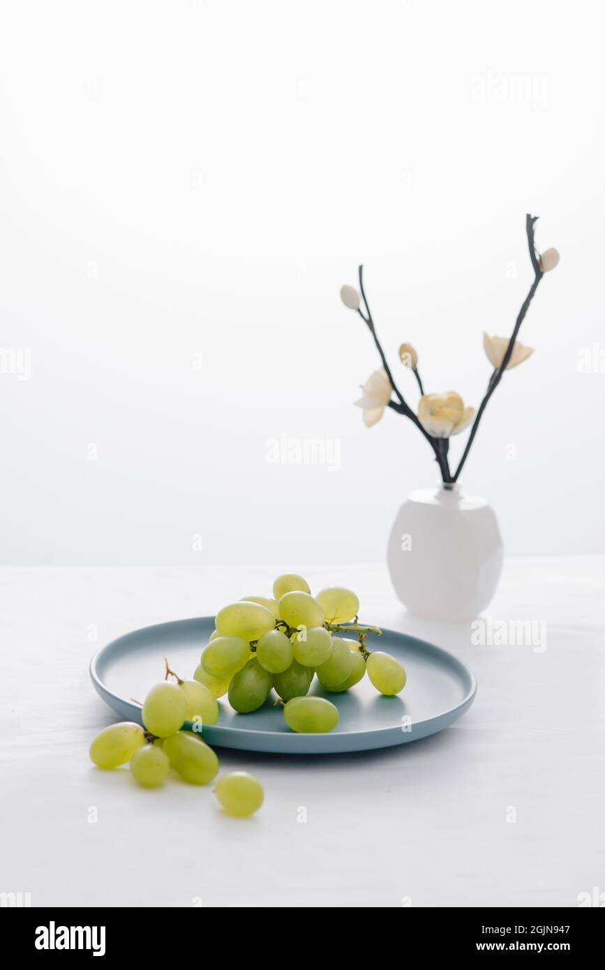 Vasen und grüne Trauben in blauer Schale auf dem Tisch Stockfoto