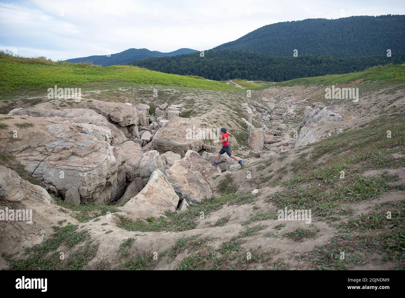 Boy springt an See Cerknica Dolinen, die trockene Seenebene im September, intermittierende See Cerknica, Slowenien Stockfoto