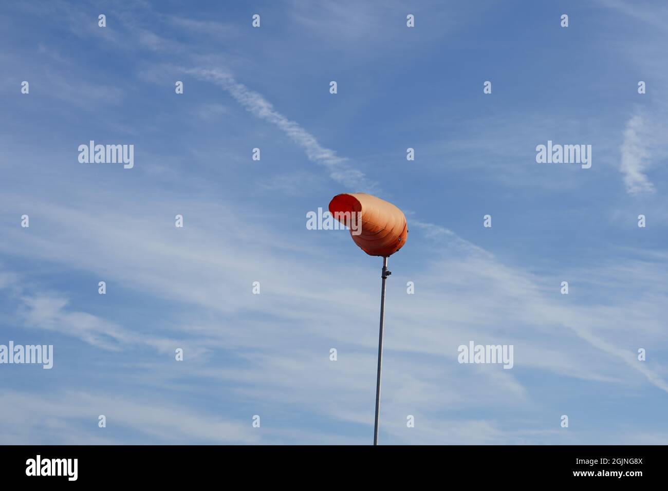 Orangefarbene Windsocke, die auf starken Wind in einem Flughafen hinweist. Stockfoto