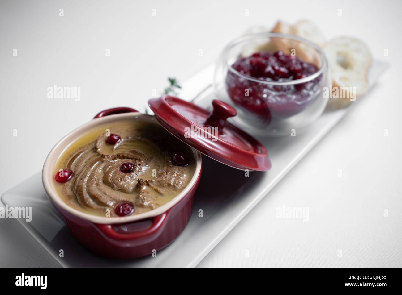 Nahaufnahme der Leberpastete aus Gänsefleisch mit Cranberry und Brot auf weißem Hintergrund Stockfoto