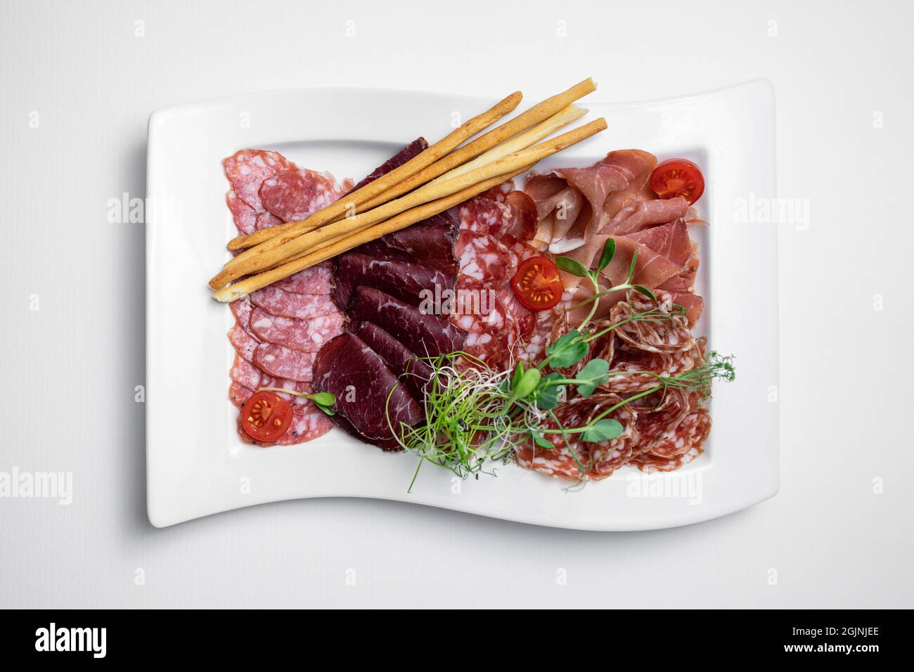 Draufsicht auf kalten Fleischteller mit Salami, Prosciutto, Wurst und Brotstäbchen Stockfoto