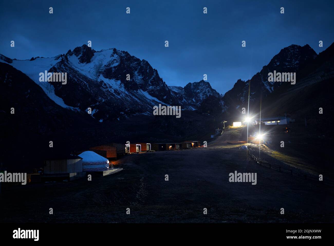 Schöne Landschaft Hotelresort mit Jurtenhaus in Shymbulak in der Nacht gegen Schneeberge in Almaty, Kasachstan. Stockfoto