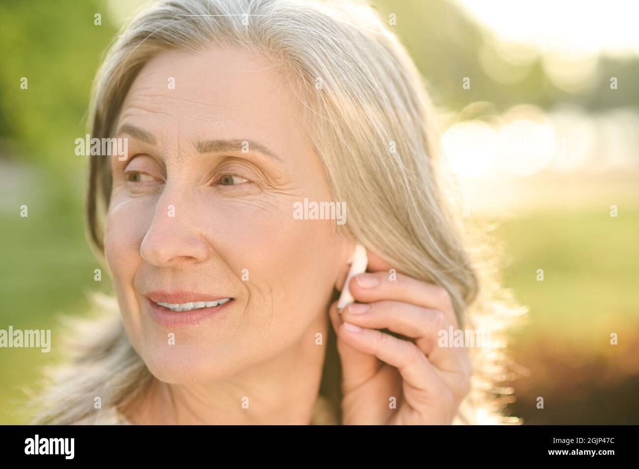 Frau berührt den kabellosen Kopfhörer im Ohr Stockfoto