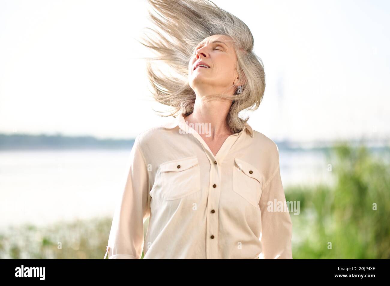 Grauhaarige energische Frau mit im Wind flatternden Haaren Stockfoto