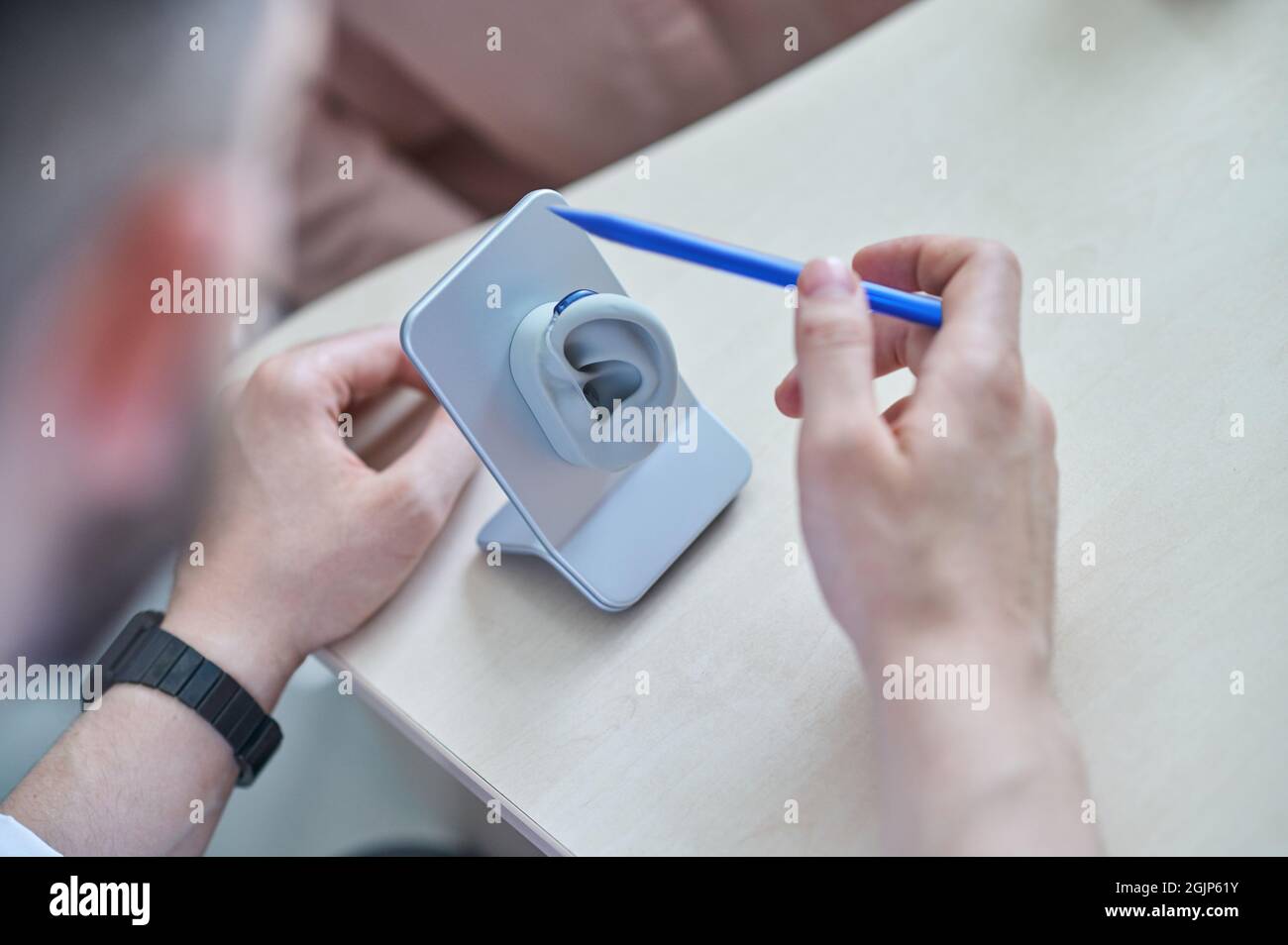 Arzt, der dem Patienten Hörgeräte zeigt Stockfoto