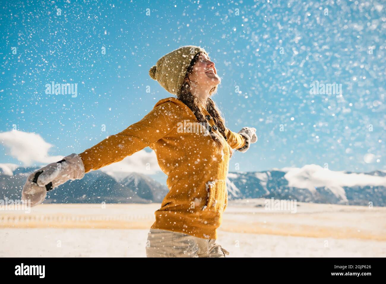 Junge glücklich stilvolle Mädchen wirbelt mit erhobenen Händen und genießt den Schnee in den Bergen. Konzept für Winterferien Stockfoto