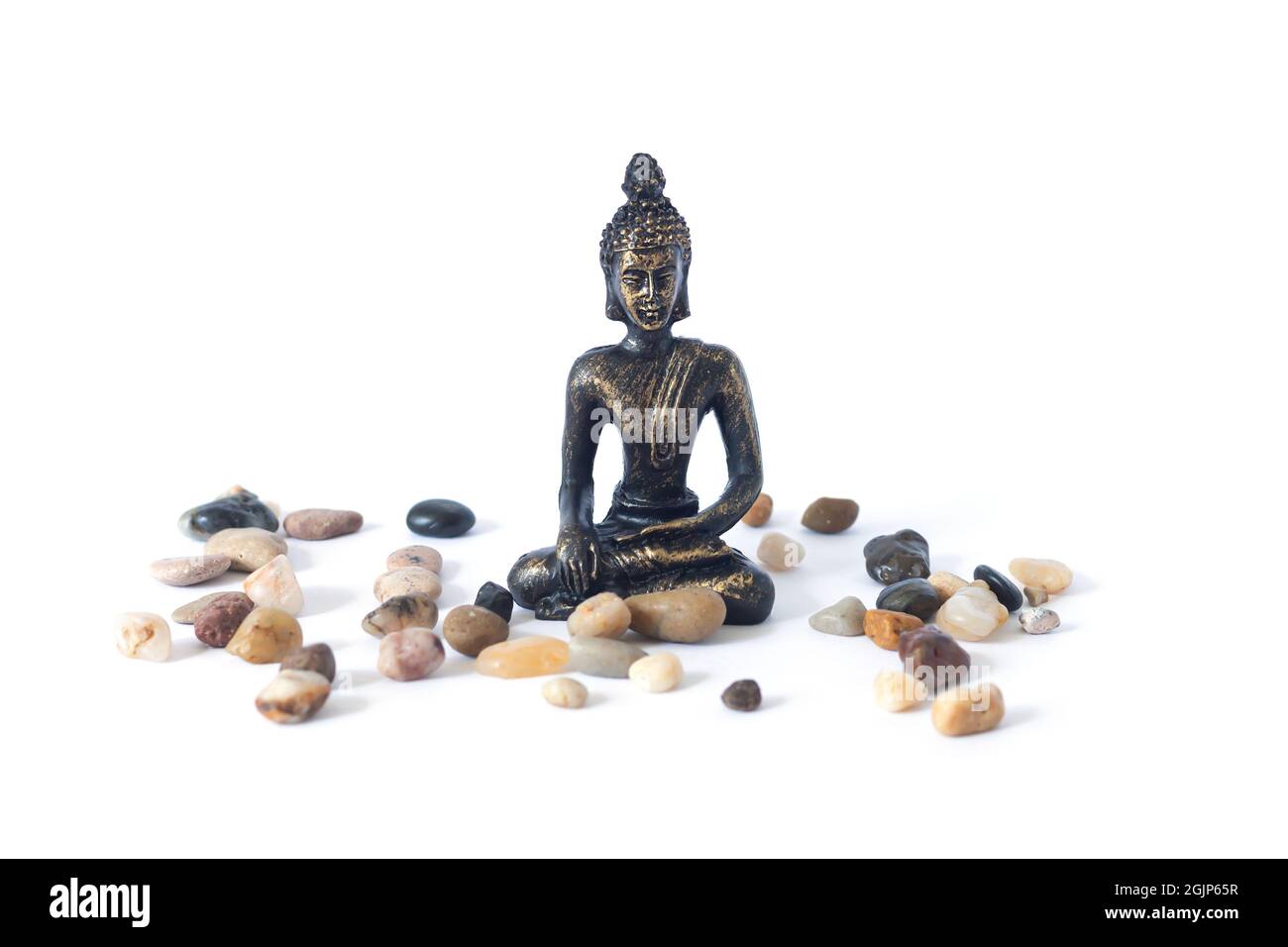 Meditierende Buddha-Statue mit Kieselsteinen isoliert auf weißem Hintergrund. Zen-Garten oder Meditationsort Konzept Stockfoto