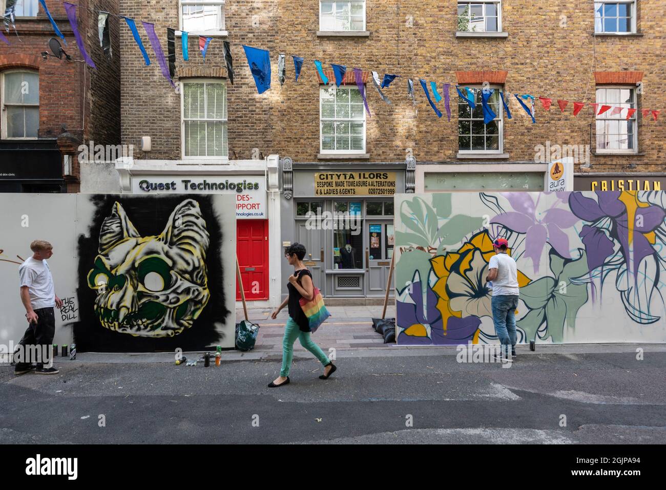 London, Großbritannien. 11. September 2021. Eine Frau passiert Straßenkünstler The Real Dill (L) und Nerone bei der Arbeit, während die Menschen die Rückkehr der jährlichen Whitecross Street Party in der Whitecross Street in der Nähe von Barbican für das Wochenende genießen. Neben Performance- und Gemeinschaftsveranstaltungen malen mehrere Straßenkünstler live für den Aufstieg der Nonconformists-Freiluftausstellung. Seit 2010 huldigt die Veranstaltung den prominenten Nonkonformisten William Blake, Daniel Defoe, John Bunyan und Susannah Wesley, die auf dem nahe gelegenen Bunhill Fields Begräbnisplatz zur Ruhe gebracht wurden. Kredit: Stephen Chung / Alamy Live Nachrichten Stockfoto