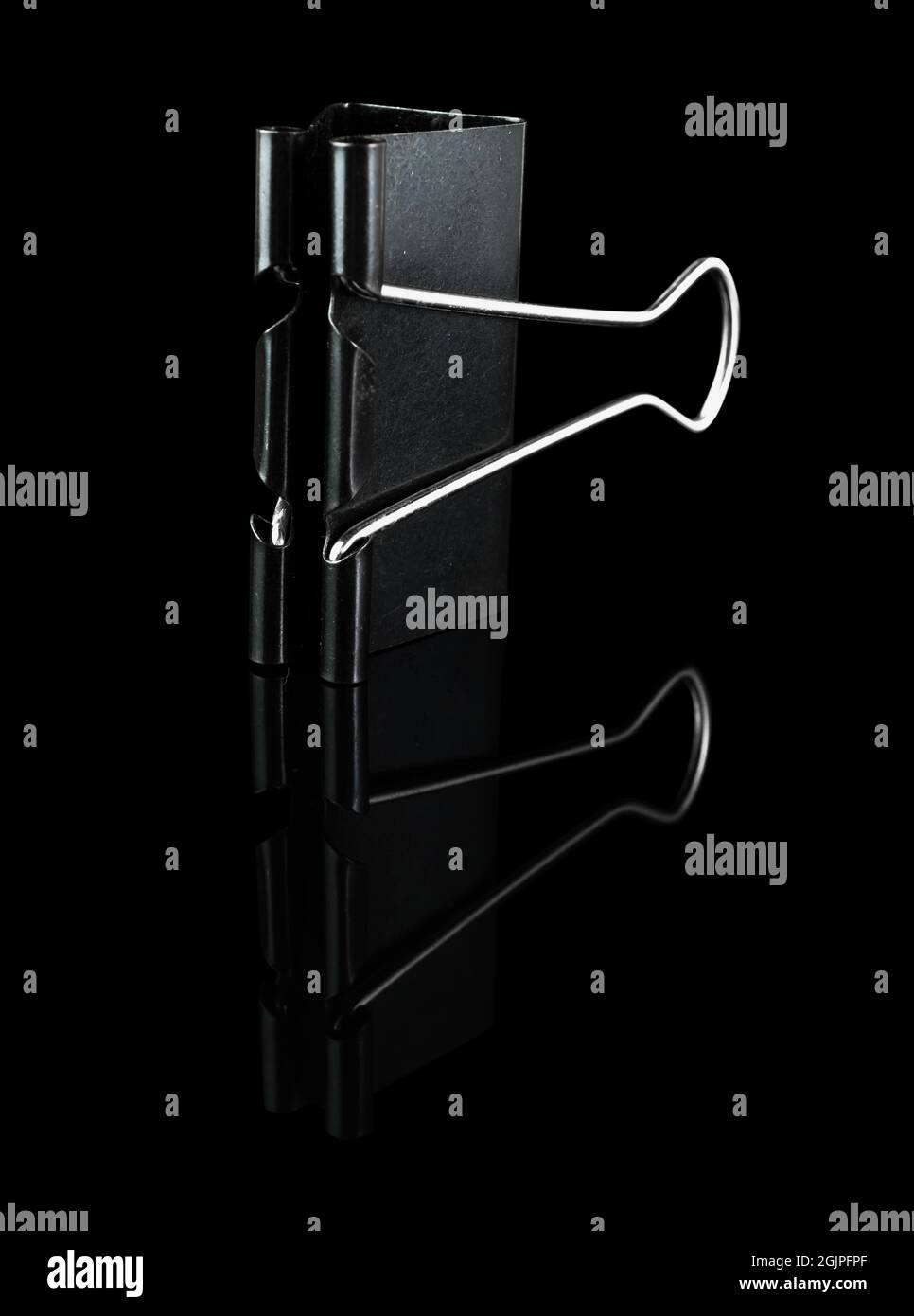 Schreibwarenclip aus Metall, Binder, schwarz, auf schwarzem Hintergrund, mit Reflektion Stockfoto