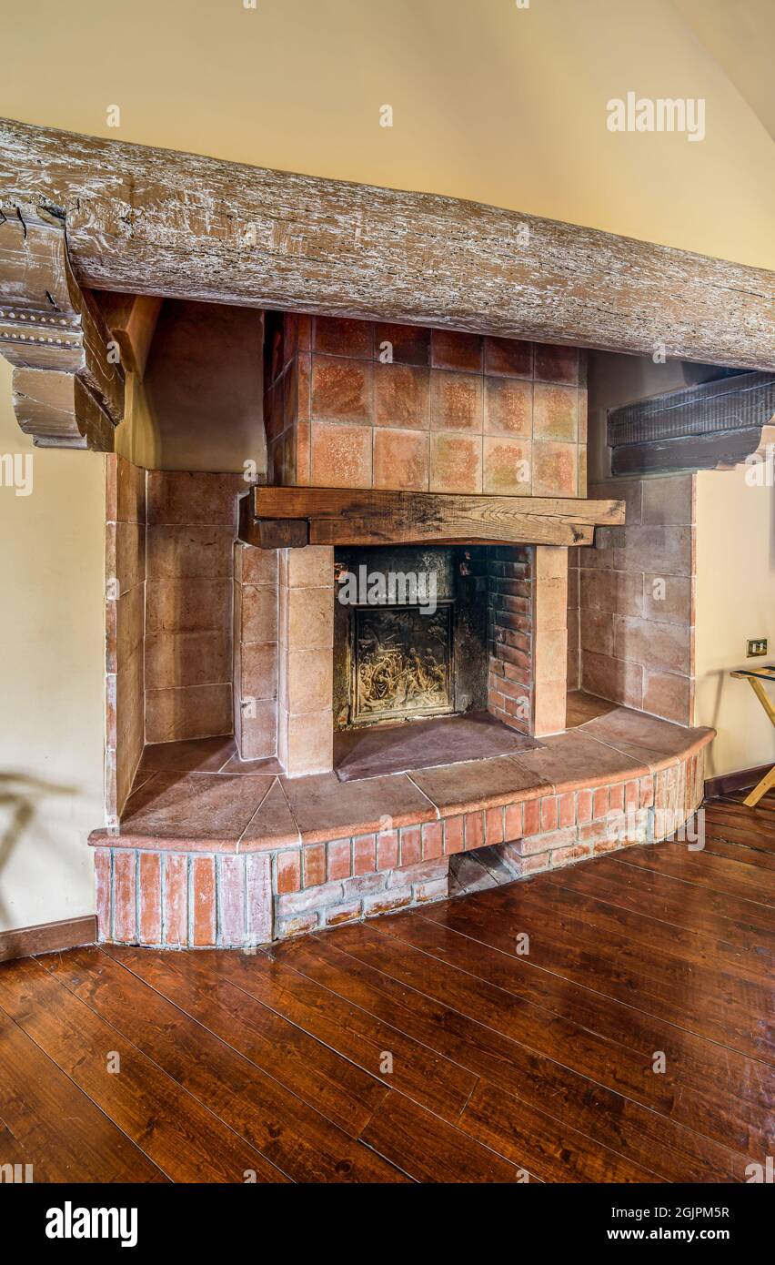 Rustikaler Ziegelkamin mit antikem Holzbalken im Inneren des Hauses, Innendekor-Konzept. Stockfoto