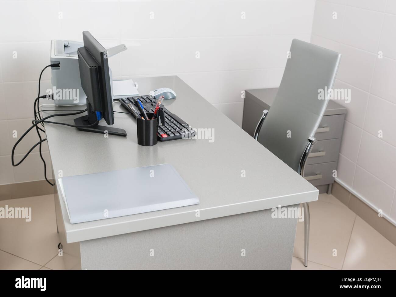 Ein medizinisches Büro mit weißen Wänden und ein Arztarbeitsplatz mit Tisch und Büroausstattung. Niemand Stockfoto