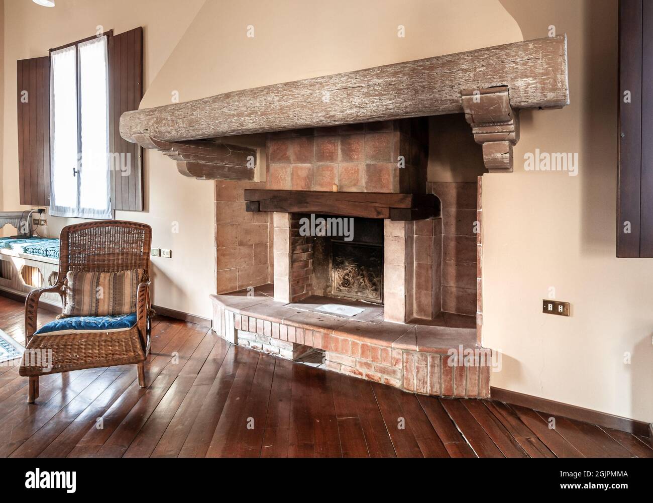 Rustikaler Ziegelkamin mit antikem Holzbalken im Inneren des Hauses, Innendekor-Konzept. Stockfoto