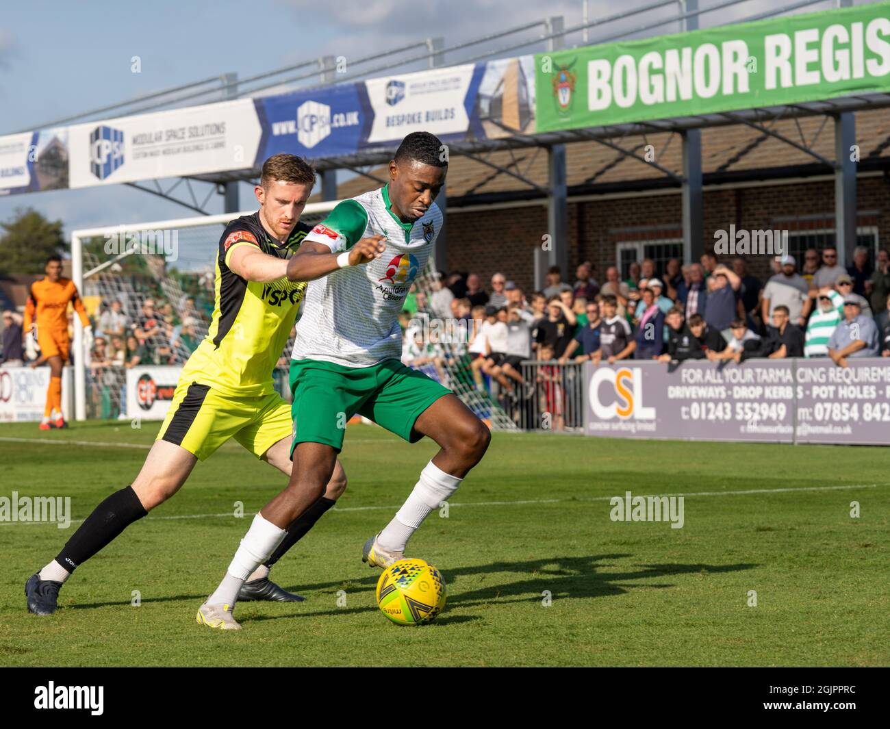 Bognor Regis, Großbritannien, 11. Sep 2021. Action von Isthmian Premier League (Southern) Football (Soccer) mit den „Rocks“ (Bognor Regis Town FC gegen Carshalton). Zwei ethnisch unterschiedliche Spieler tageln sich vor einem gepackten Stand um den Ball. Quelle: Lyn Phillips/Alamy Live News Stockfoto