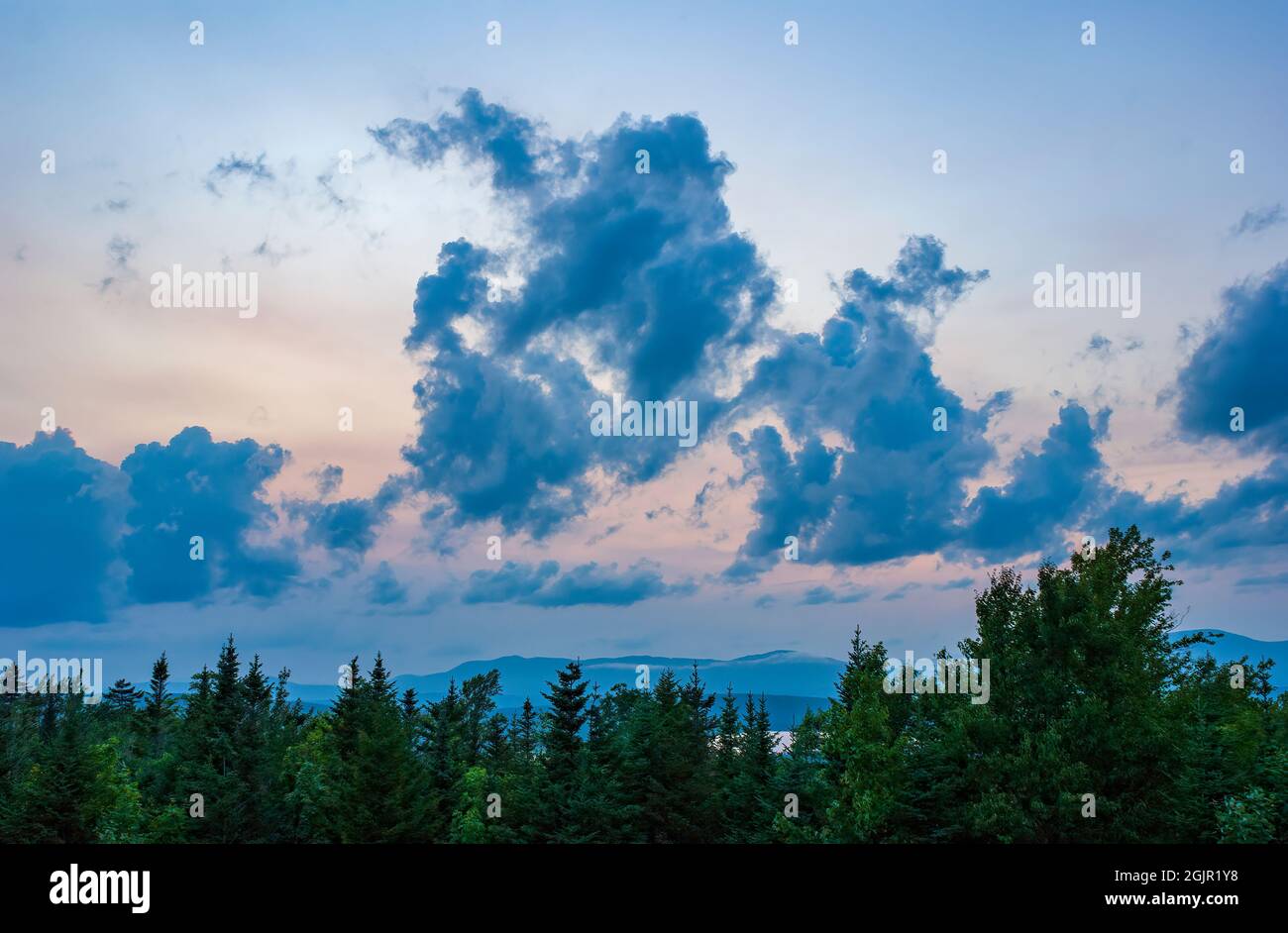 Sonnenuntergang Wolkenlandschaft über Rangeley Lake, ICH, USA. Stratocumulus castellanus Wolken über einem schwarzen Fichten-Balsam-Tannenwald. Bergkämme am Horizont. Stockfoto