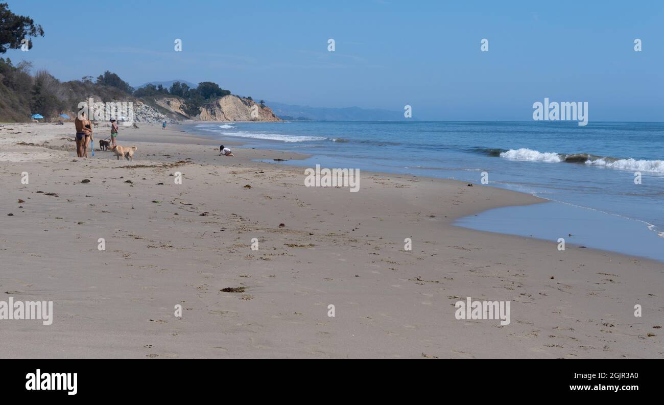 Ein Kind spielt im Sand, während andere Menschen und Hunde in der Nähe von  Summerland Beach, Summerland, Kalifornien, USA, stehen Stockfotografie -  Alamy