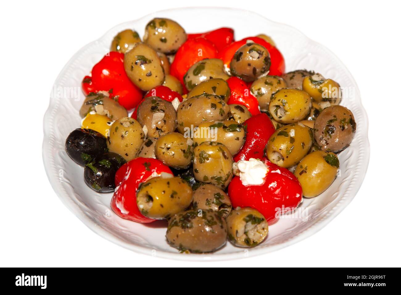 Eingelegte Oliven mit gefüllten Paprika auf einem weißen Teller, isoliert auf weißem Hintergrund Stockfoto