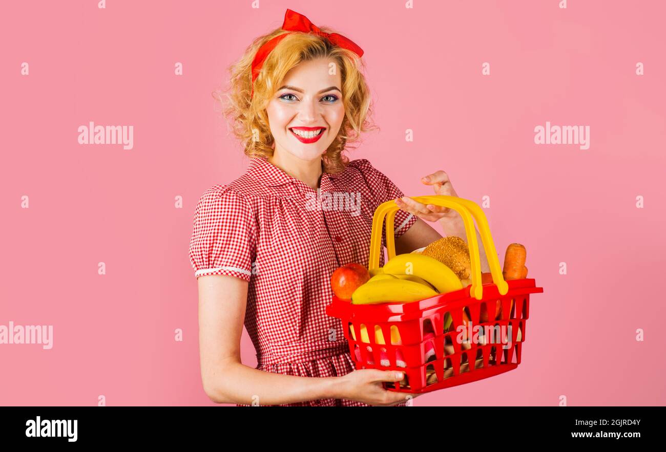 Lächelnde Frau mit Einkaufskorb mit Lebensmitteln im Supermarkt. Einkaufsbummel. Stockfoto