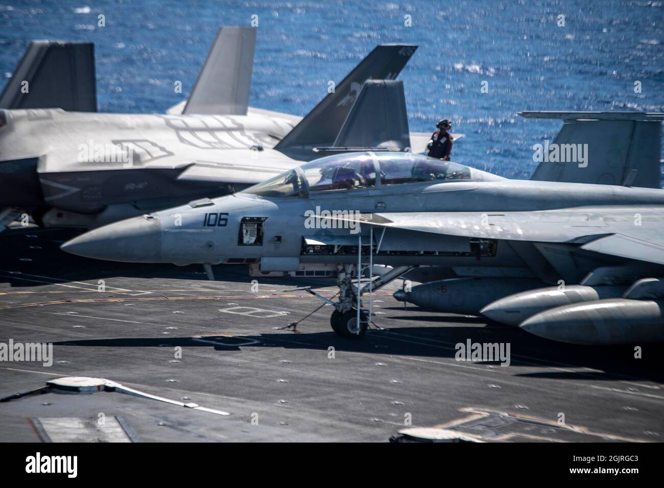 210911-N-YN807-2040 SÜDCHINESISCHES MEER (SEPT 11, 2021) Ein Seemann reinigt eine F/A-18F Super Hornet, die den „Bounty Hunters“ der Strike Fighter Squadron (VFA) 2 zugewiesen wurde, auf dem Flugdeck an Bord des Nimitz-Klasse Flugzeugträgers USS Carl Vinson (CVN 70), 11. September 2021. Die Carl Vinson Carrier Strike Group ist im operativen Bereich der 7. Flotte der USA im Einsatz, um die Interoperabilität durch Allianzen und Partnerschaften zu verbessern und gleichzeitig als einsatzbereite Kraft für eine freie und offene Region im Indo-Pazifik-Raum zu dienen. (USA Navy Foto von Mass Communication Specialist Seaman Megan Alexander) Stockfoto