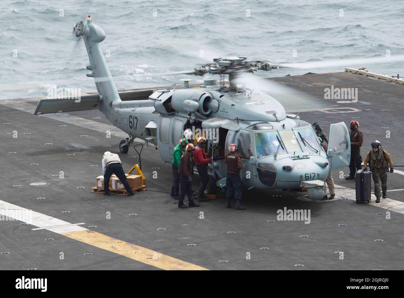 210910-N-JO823-1176 ARABIAN SEA (SEPT 10, 2021) – Seeleute entladen Fracht von einem Hubschrauber der MH-60S Sea Hawk, der an den „Goldenen Falken“ des Helicopter Sea Combat Squadron (HSC) 12 befestigt ist, auf dem Flugdeck des Flugzeugträgers USS Ronald Reagan (CVN 76) im Arabischen Meer, 10. September. Ronald Reagan ist das Flaggschiff der Carrier Strike Group 5 und wird im Einsatzgebiet der 5. US-Flotte zur Unterstützung von Marineoperationen eingesetzt, um die maritime Stabilität und Sicherheit in der Zentralregion zu gewährleisten. Verbindung des Mittelmeers mit dem Pazifik durch den westlichen Indischen Ozean und drei strategische Engpässe Stockfoto