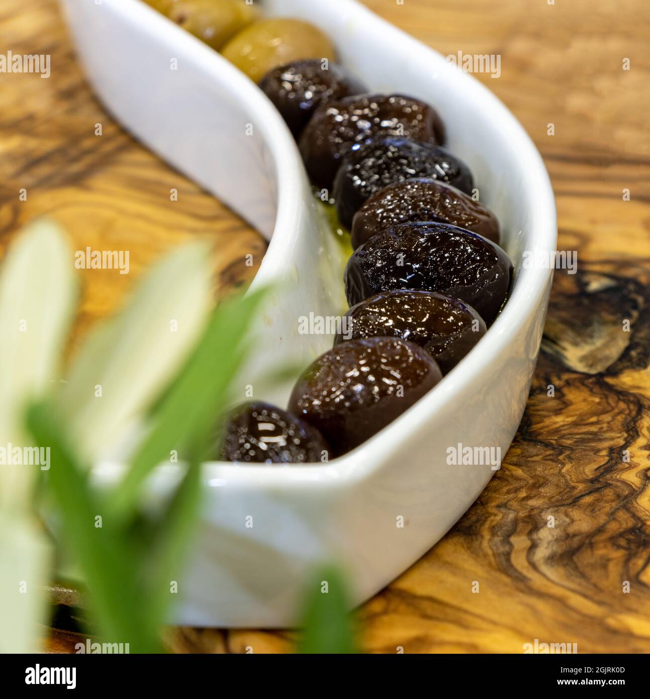 Nahaufnahme von schwarzen und grünen Oliven in Holzschüssel Stockfoto
